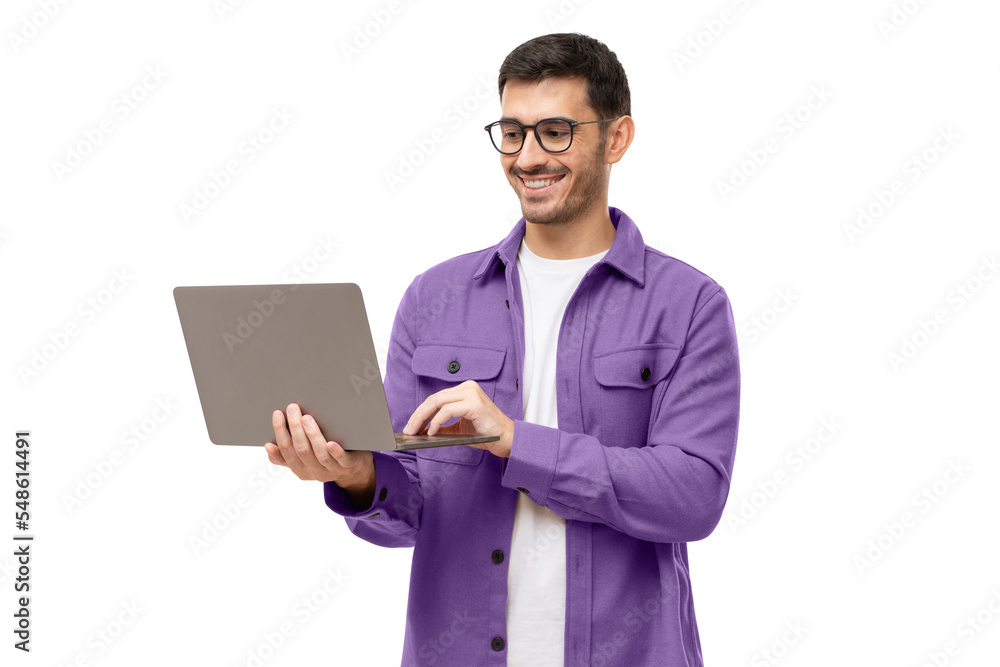 Young stylish man wearing casual purple shirt, standing with opened laptop, surfing online or typing