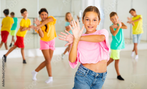 Fototapeta Naklejka Na Ścianę i Meble -  Positive girl exercising in group of classmates during dance class at school