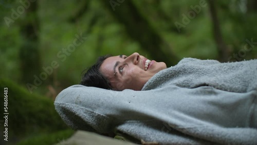 Close up of Happy young attractive female laying on wooden bridge in forest