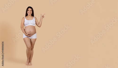 Maternity Ad. Beautiful Pregnant Lady In Underwear Pointing Aside At Copy Space © Prostock-studio