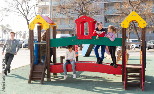 Obraz na plátne Little boy addicted with mobile gadget sitting on jungle gym while his friends r