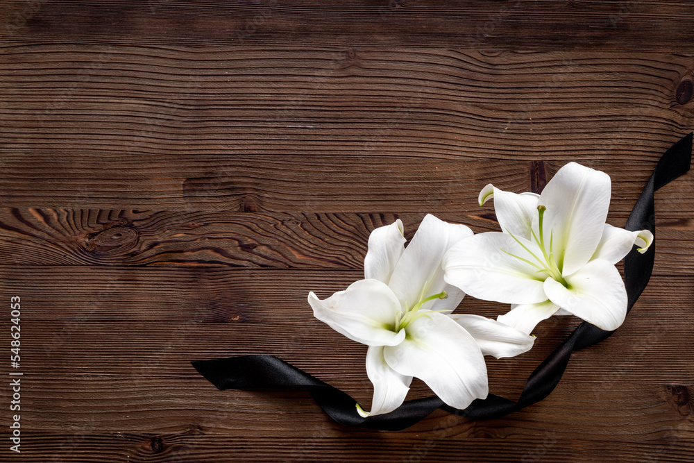 Two white liles flowers with black ribbon. Mourning or funeral background Two white liles flowers with black ribbon. Mourning or funeral background