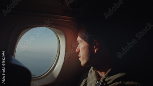Young traveling male looking out airplane window, reflecting