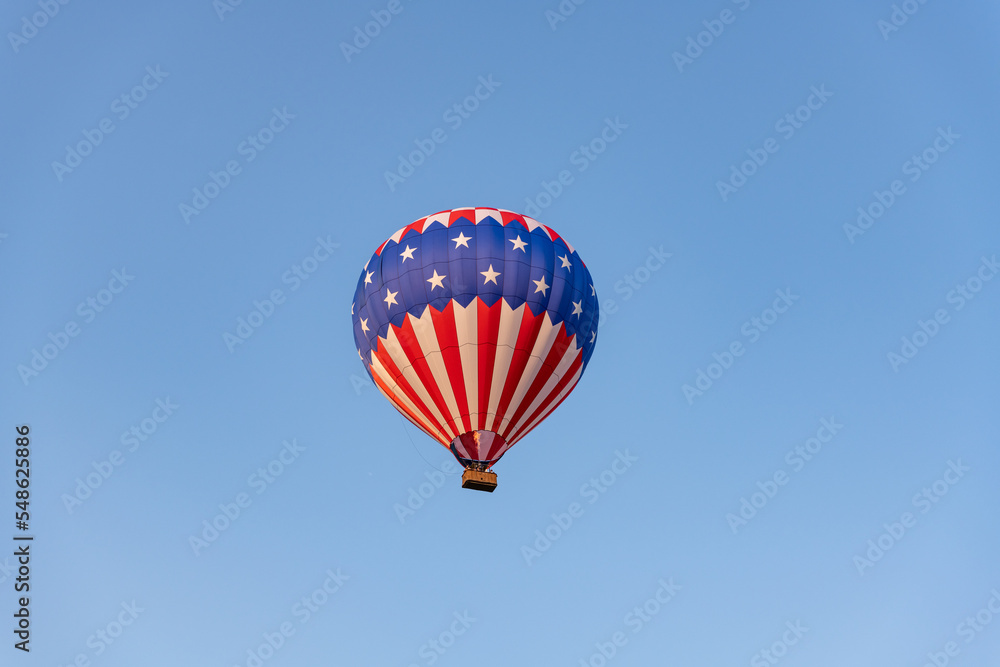 Fototapeta premium A stars and stripe hot air balloon flying high in the blue sky.