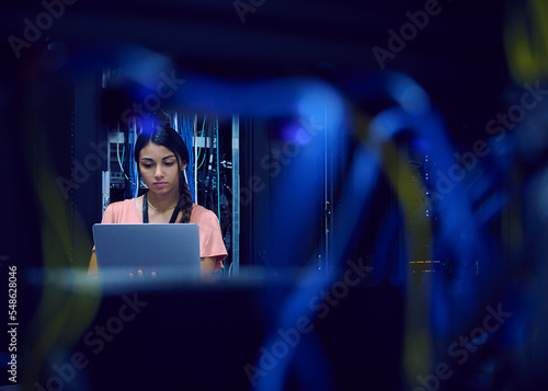 Female technician using laptop in server room