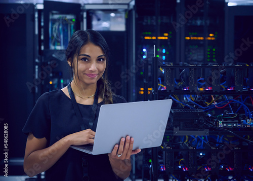 Portrait of smiling female technician with laptop in server room photo