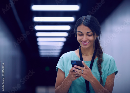Smiling female technician looking at smart phone in data center photo