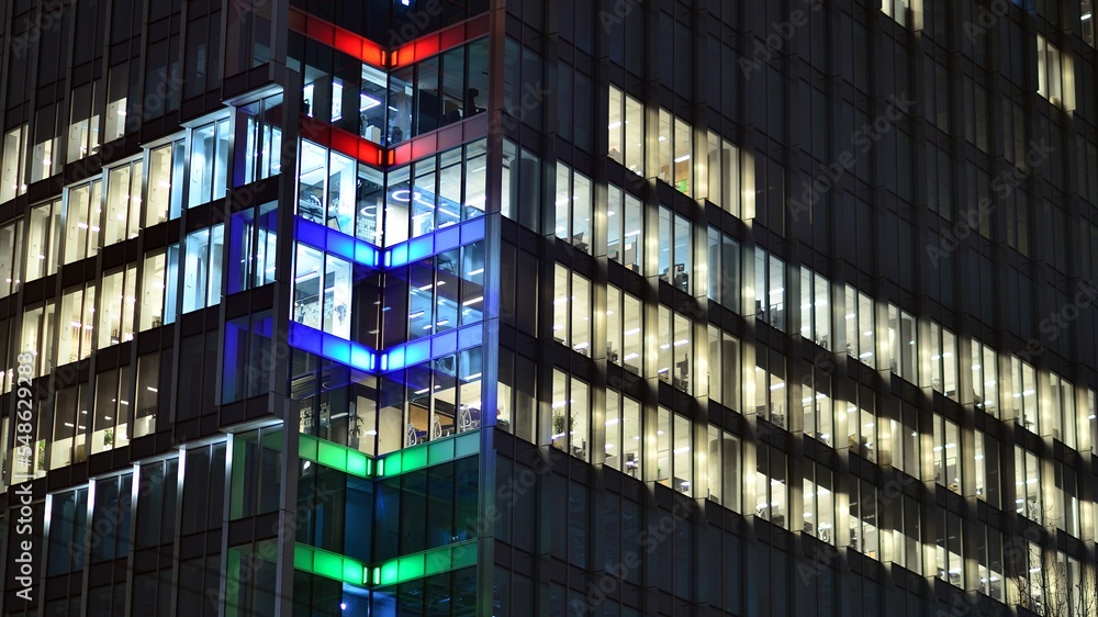 Modern office building in city at the night. View on illuminated offices of a corporate building. Blinking light in window of the multi-storey building of glass and steel. Long exposure at night Modern office building in city at the night. View on illuminated offices of a corporate building. Blinking light in window of the multi-storey building of glass and steel. Long exposure at night