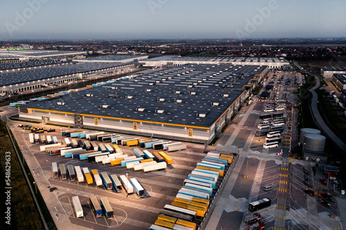 Top view of many trailers and containers near the logistics warehouse, in the evening