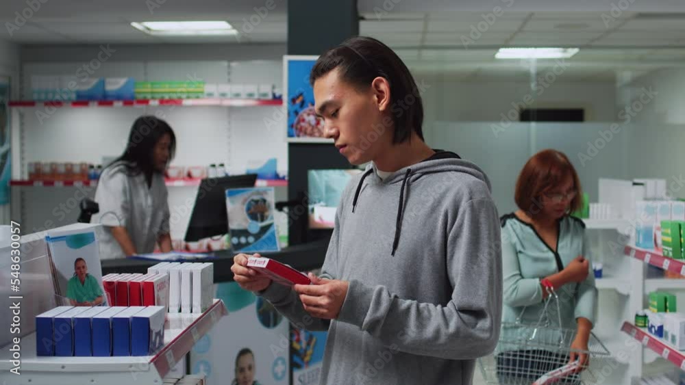 Asian customer checking pills boxes on pharmacy shelves, looking at packages to find treatment and drugs. Reading leaflets to buy supplements and pharmaceutical products at medical store. Asian customer checking pills boxes on pharmacy shelves, looking at packages to find treatment and drugs. Reading leaflets to buy supplements and pharmaceutical products at medical store.