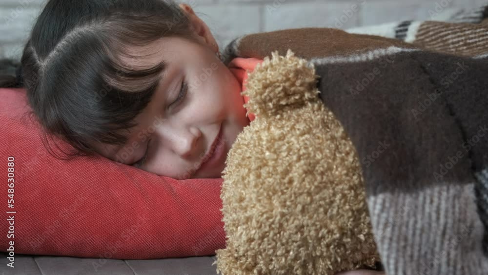 Sleep hugging teddy. A child has a cozy time with her plush bear under the blanket in the room. Sleep hugging teddy. A child has a cozy time with her plush bear under the blanket in the room.