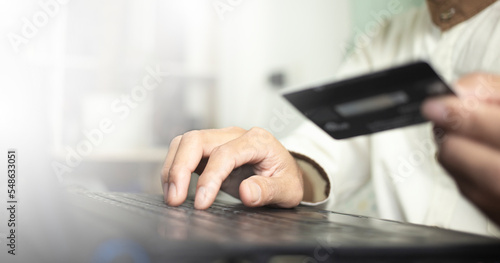 person typing on laptop and holding credit card, online shopping with credit card