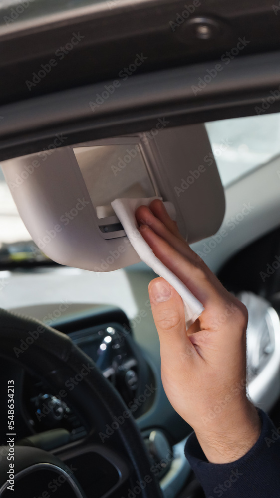 Man cleaning mirror with wet wipe in car, closeup. Protective measures