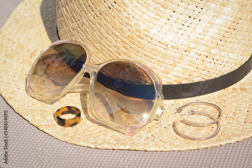 Stylish hat, sunglasses and jewelry on grey surface, closeup