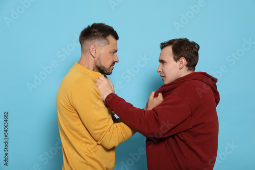Quadro em tela Two emotional men fighting on light blue background