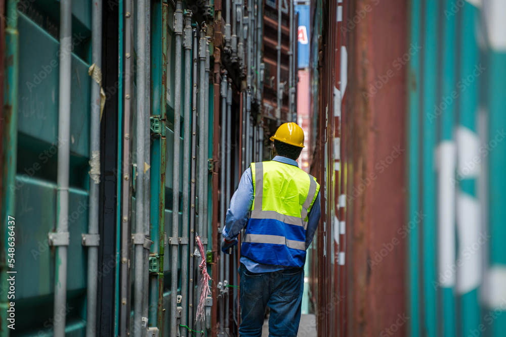 Engineer or foreman checking inventory or job details with cargo container background,Logistic import export working concept. Engineer or foreman checking inventory or job details with cargo container background,Logistic import export working concept.