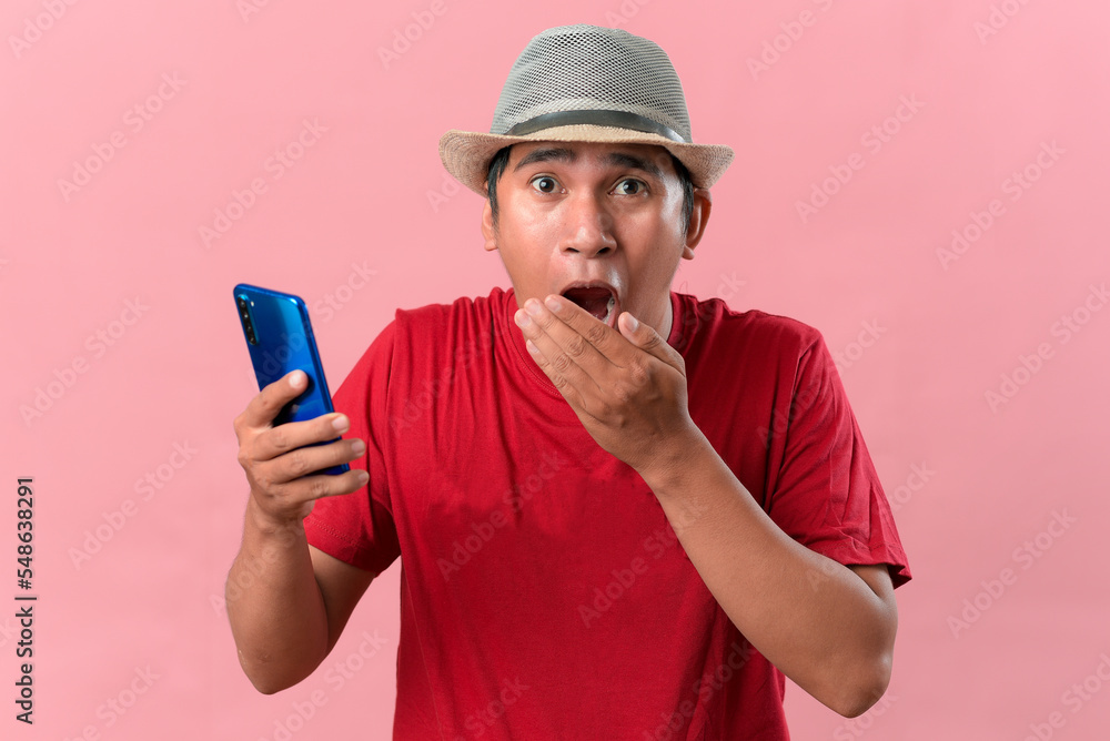 Close-Up of shocked Asian man using mobile phone Close-Up of shocked Asian man using mobile phone