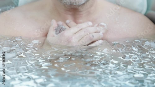 Cropped Portrait Of A Man Submerged In Cold Water With Ice Cubes. Ice Bath, Wim Hof Method. closeup photo