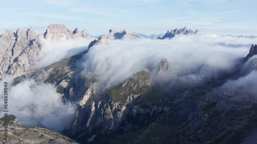 Low clouds at sunrise flowing over jagged landscape of Italian Dolomites, aerial Low clouds at sunrise flowing over jagged landscape of Italian Dolomites, aerial