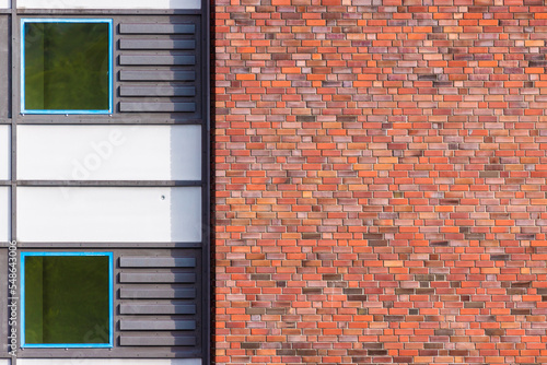 Facade detail of a building with brick wall, blue window frames and metal cladding (ID: 548643006)
