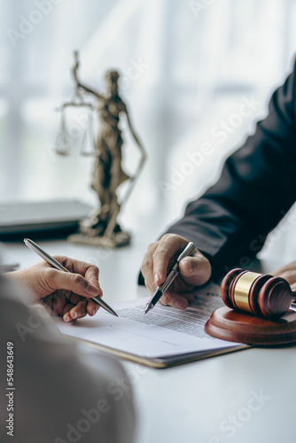Business lawyers working on law in a courtroom help clients read legal documents and study information about court cases, along with a justice scale and hammer. photo
