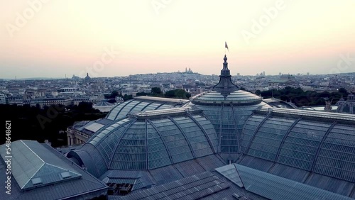 Aerial tour above the iconic Grand Palais near Champs Elysees and Alexander III bridge, Paris, France, featuring historic Paris city in backdrop and Sacré-Cœur at the horizon in morning photo