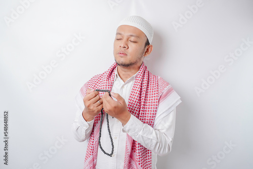 Happy handsome Asian Muslim man is praying to God. photo