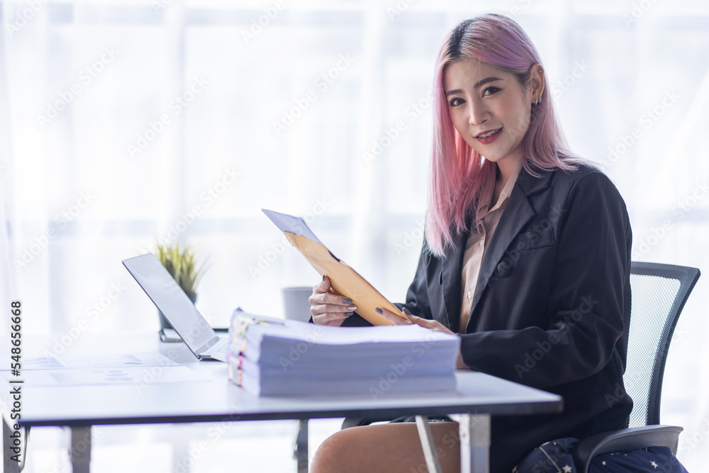 Smile Young business Asian woman freelancer is working her job on a laptop computer in a modern office. Doing accounting analysis report real estate investment data, Financial and tax systems concept. Smile Young business Asian woman freelancer is working her job on a laptop computer in a modern office. Doing accounting analysis report real estate investment data, Financial and tax systems concept.