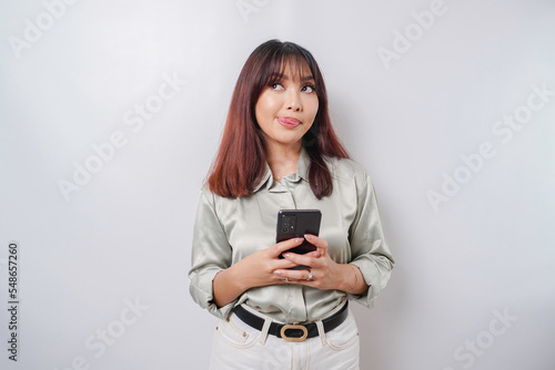 Photo of a hungry excited young woman holding her phone and wondering what to order yummy food isolated on white color background