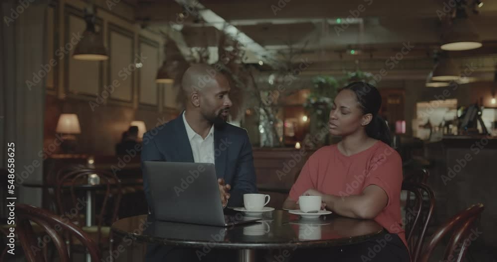 Two Businesspeople using Laptop and having a Meeting in a Restaurant Two Businesspeople using Laptop and having a Meeting in a Restaurant