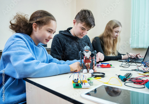 Diverse teenager pupils build robot, learn at table at STEM engineering science education class.