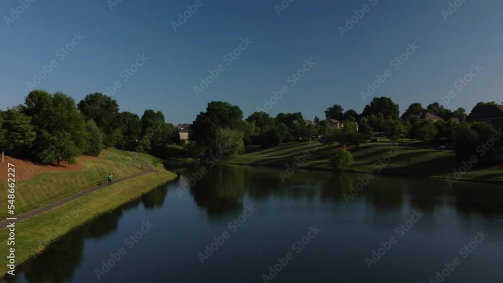 Slow aerial pan reveal of pond in a neighborhood.