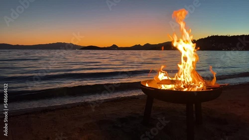 Burning fire pit at beach. Beautiful sunset and sea view with sparkling firewood flames. Happy weekend campfire activity. Cozy beach party with fireplace. Romantic vacation background with copy space. photo