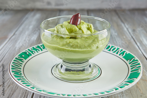 Avocado mousse with olives in transparent glass cup, on plate photo