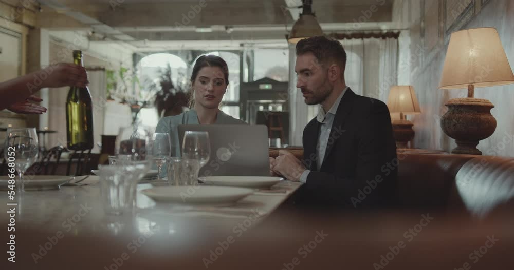 Two Businesspeople having a Meeting in a Restaurant, Using Laptop Technology Two Businesspeople having a Meeting in a Restaurant, Using Laptop Technology