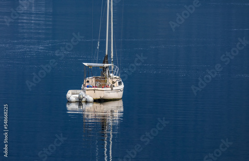 Boat or yahct in a calm lake water, wooden fishing boat in a still lake water. View of a white boat in the blue water photo