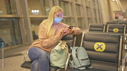 an emigrant woman in an airplane seat watching the news on her phone
