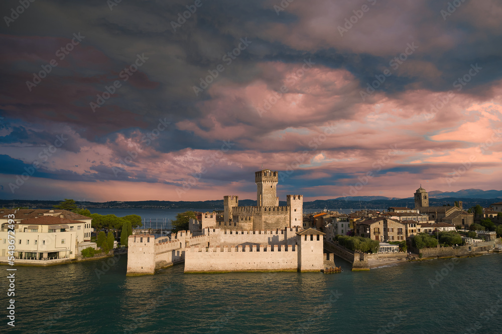 Scaligero Castle against the backdrop of pink storm clouds at sunrise top view. Thunderclouds over Scaligero Castle aerial view.