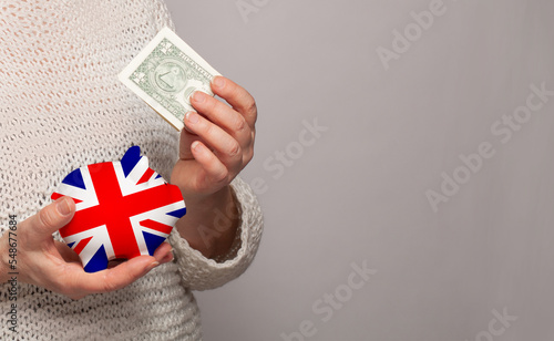 Flag of UK on money bank in English woman hands. Dotations, pension fund, poverty, wealth, retirement concept