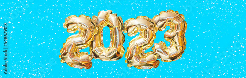 Helium golden balloon number of year 2023. Glowing festive garland with bokeh on blue background. Happy New Year banner