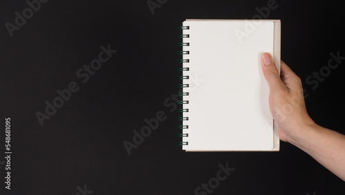 Hand is holding notebook isolated on black background