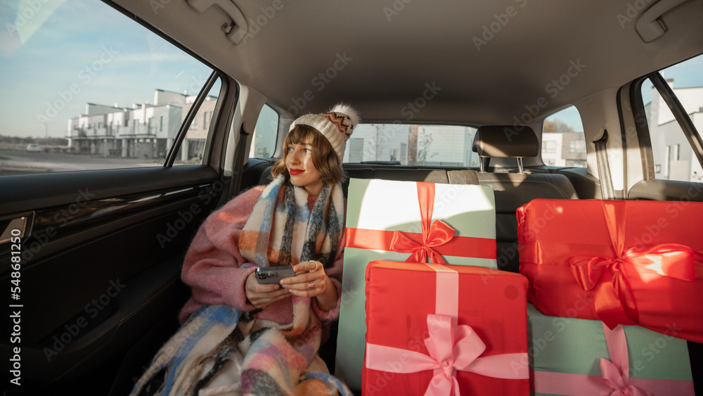 Woman in car with Christmas presents - obrazy, fototapety, plakaty 