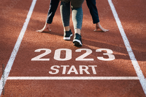 happy new year 2023 symbolizes the start of the new year. Rear view of a man preparing to run on the athletics track engraved with the year 2023. The goal of Success.Getting ready for the new year
