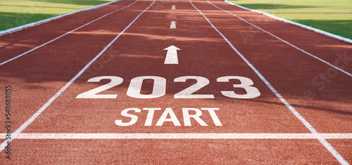 happy new year 2023 symbolizes the start of the new year. Rear view of a man preparing to run on the athletics track engraved with the year 2023. The goal of Success.Getting ready for the new year photo