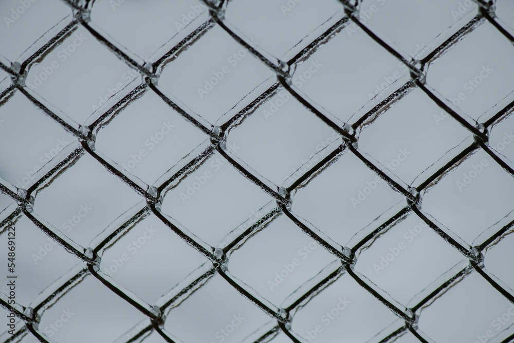 Naklejka premium Metal mesh with a layer of ice on it during freezing rain in winter, frostbite and environment, weather