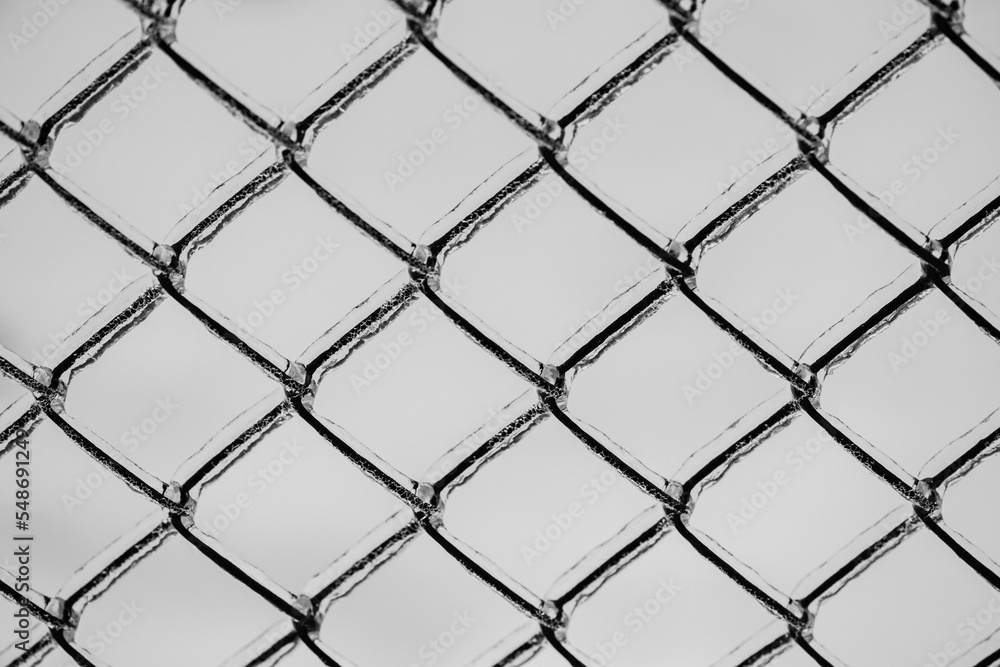 Naklejka premium Metal mesh with a layer of ice on it during freezing rain in winter, frostbite and environment, weather