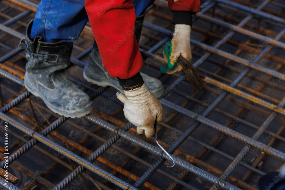 Worker welds reinforcing mesh. Male workers are working on a retaining wall, knitting rebar and reinforcing bar on the construction site. Worker welds reinforcing mesh. Male workers are working on a retaining wall, knitting rebar and reinforcing bar on the construction site.