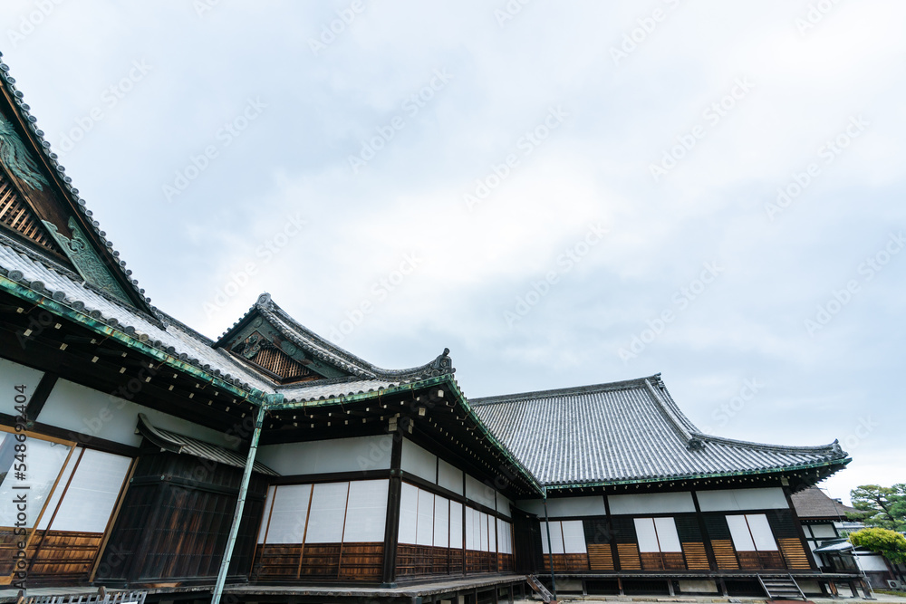 Kyoto, Japan - April 17, 2018: low angle shot of a corner of the ninomaru imperial palace building against sunny blue sky at nijo castle at springtime