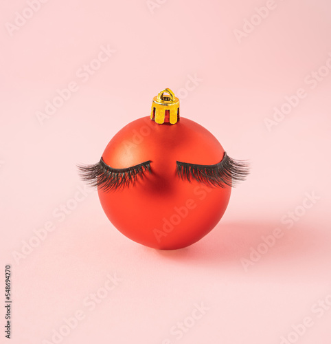 minimal creative christmas composition of red new year bauble with eyelush on pastel pink background. photo