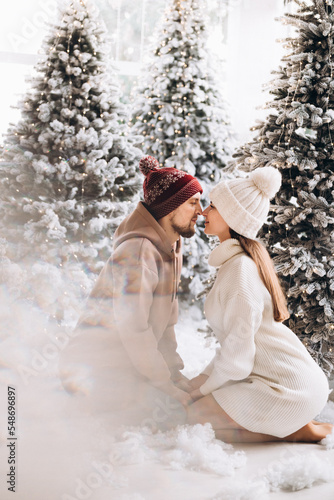 A couple stay on the snow in the Christmas forest